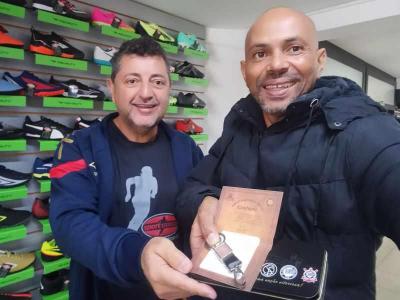 Aroldo, da Sport Stancia, presenteia Carlo, do JOGO SRIO, com produto do Corinthians